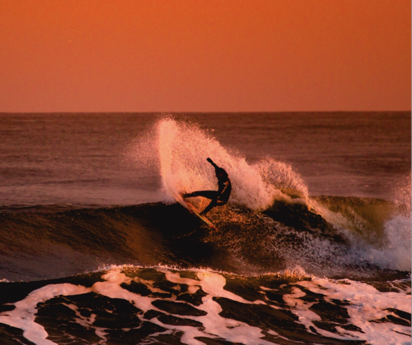 A surfer surfing at sunset