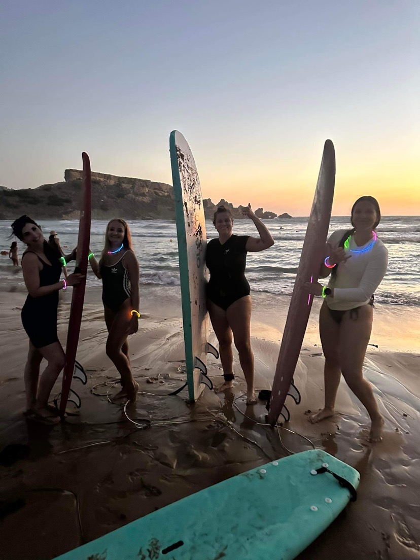 Girls pose near the surfboards at sunset