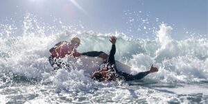 Lifeguard rescuing a surfer in turbulent ocean waves.