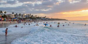 Surfers riding waves at sunset with colorful surfboards.