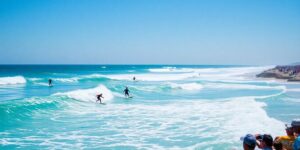 Surfers competing on vibrant waves during a sunny day.
