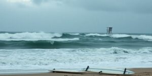 Crashing waves and surfboards on a stormy beach.