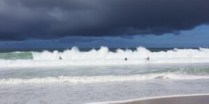 Surfers riding large waves on California beach.