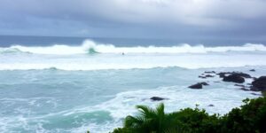 High waves crashing on rocky Hawaiian coastline.