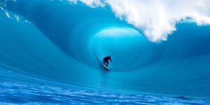 Surfer rides large blue Pipeline wave.