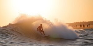 Surfer carves wave, sun glints, crowd cheers.