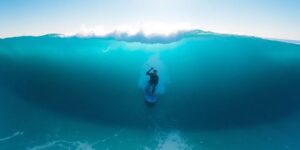 Surfer on large wave, sunny day.