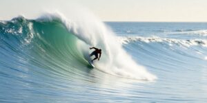 Surfer on a dynamic wave, water spraying, bright sun.