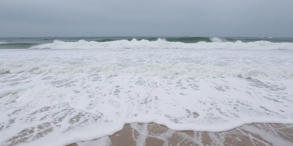 Large waves crash on a sandy beach.