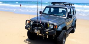 SUV on beach, surf, fishing rods.