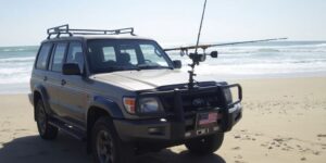 SUV on beach, surf fishing rod