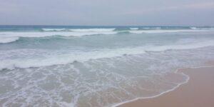 Waves crash onto a sandy beach.