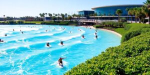 Surfers riding waves inside a large, modern surf lagoon.