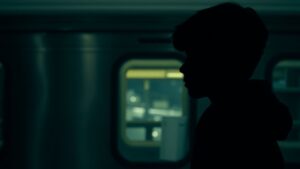 Teenager subway surfing on top of a moving train.