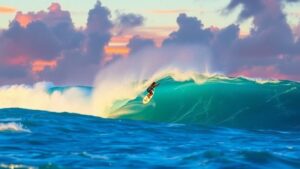 Surfer riding a massive wave at Cloud 9 during sunset.