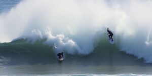 Surfers riding massive waves in a competition.