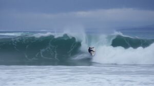Surfer battling a large wave in stormy conditions.