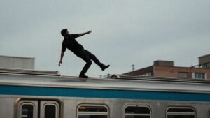 Person surfing on top of a moving subway train.