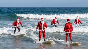 Surfers in Santa suits riding ocean waves.