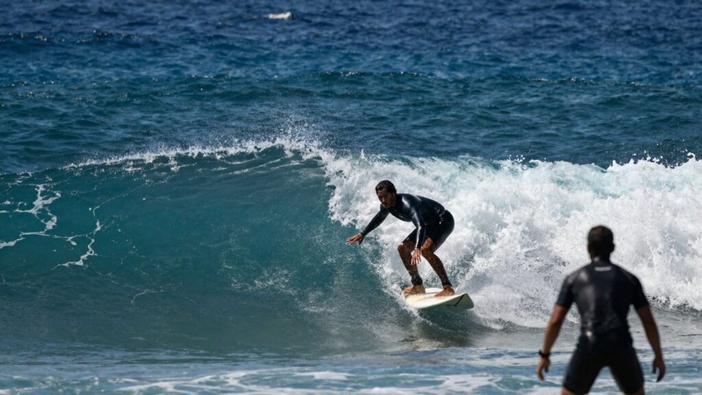 Surfers riding waves at a professional surfing competition.