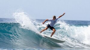 [Carissa Moore] surfing a large wave, mid-air.